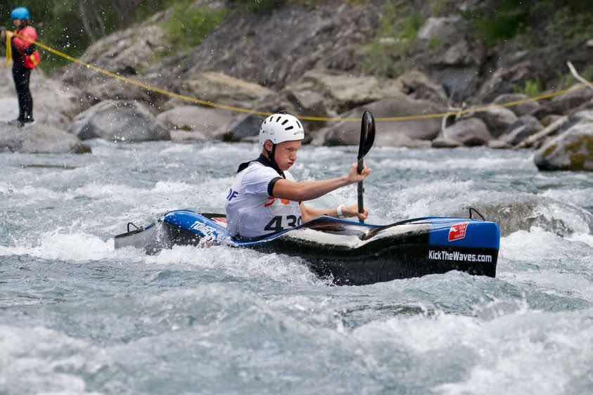 Compétiteur en kayak de Descente en action dans l'eau-vive
